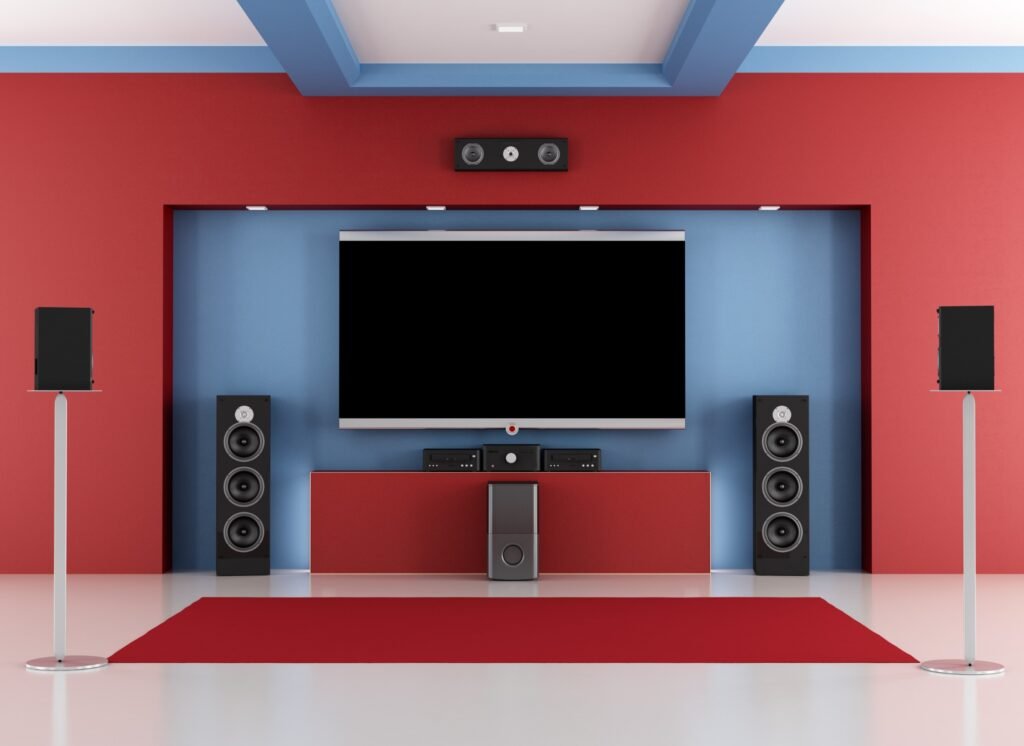 Modern home theatre with a large TV, surround sound speakers, and red and blue decor for an immersive viewing experience.