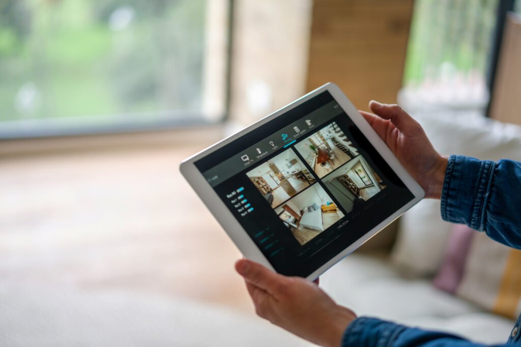Close-up on a woman monitoring all the rooms in her house with a home security system using a digital tablet - smart home concepts.